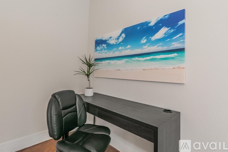 A black leather chair is positioned in front of a painting of a beach scene.