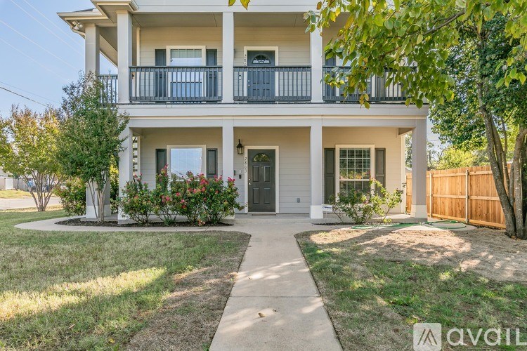 A two-story house with a balcony and a front yard.