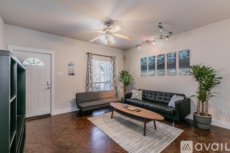 A living room with a black couch, a wooden coffee table, and a ceiling fan.