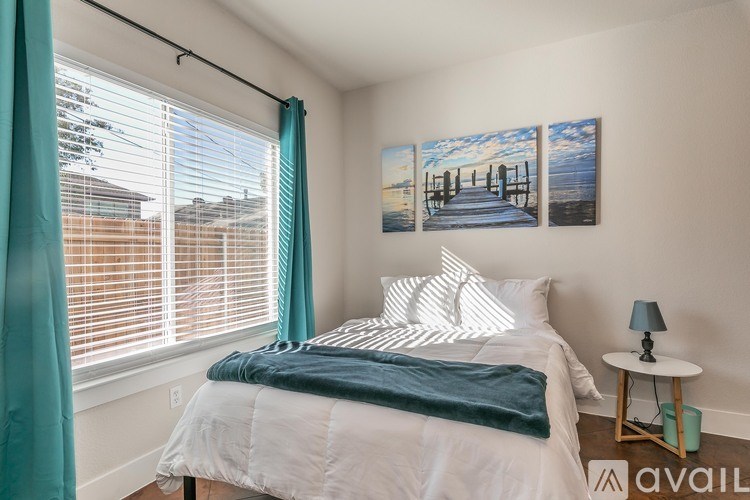 A bedroom with a bed, a nightstand, and two pictures on the wall.