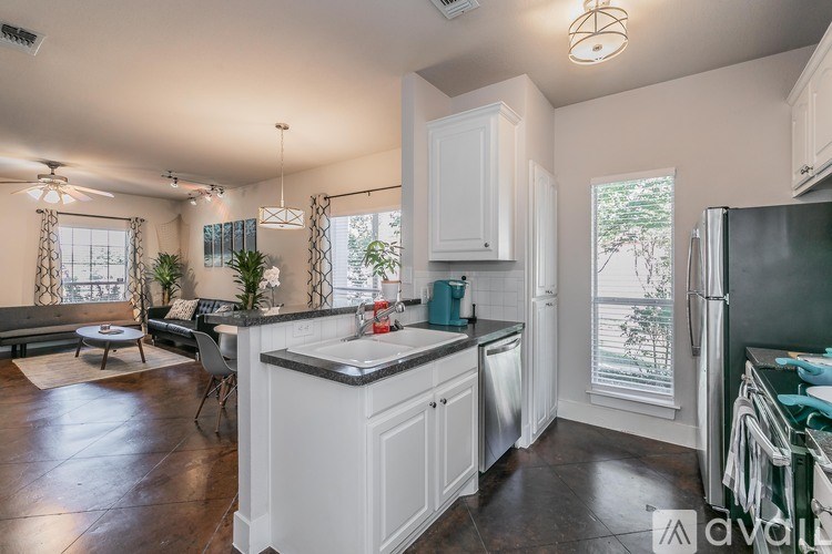 A kitchen with white cabinets and a black refrigerator.