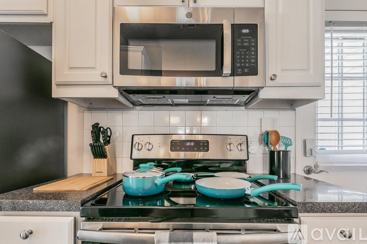 A modern kitchen with a black refrigerator and a stove with blue pots on it.