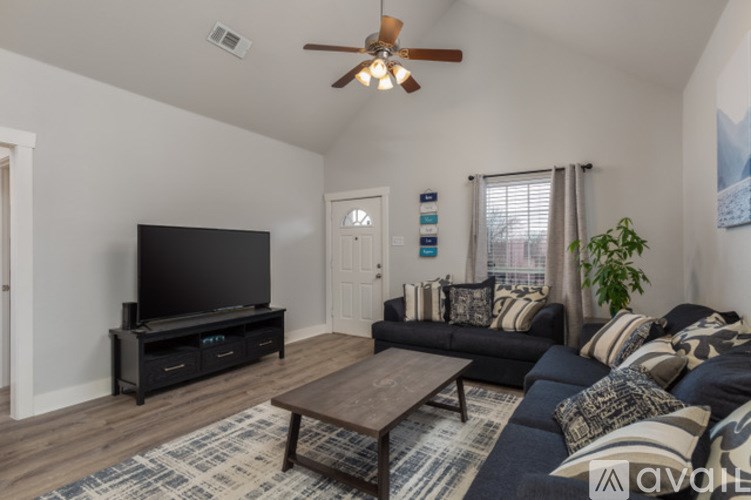 A living room with a black couch and a flat screen TV.