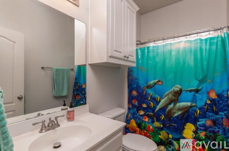A bathroom with a white sink and a shower curtain with an underwater scene on it.
