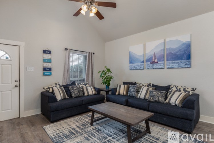 A living room with a couch, a coffee table, and a ceiling fan.