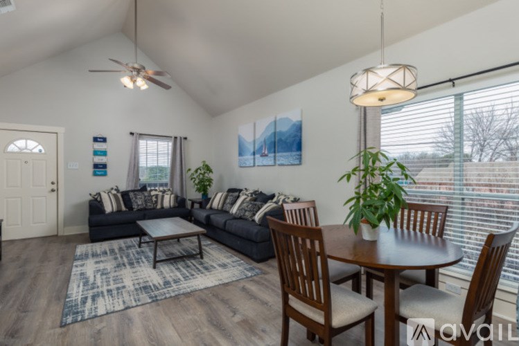 A living room with a black couch and a wooden dining table.