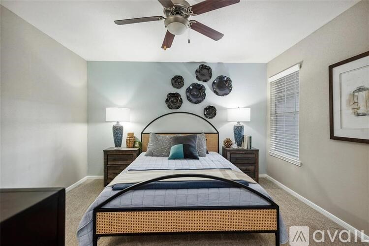 A bedroom with a bed, a ceiling fan, and wall decorations.