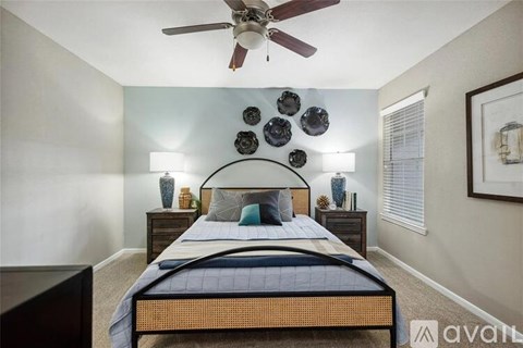 A bedroom with a bed, a ceiling fan, and wall decorations.