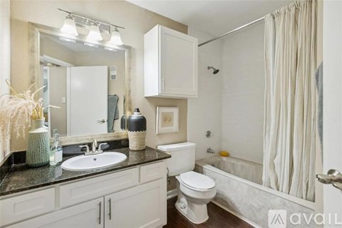 A bathroom with a white toilet, sink, and shower.