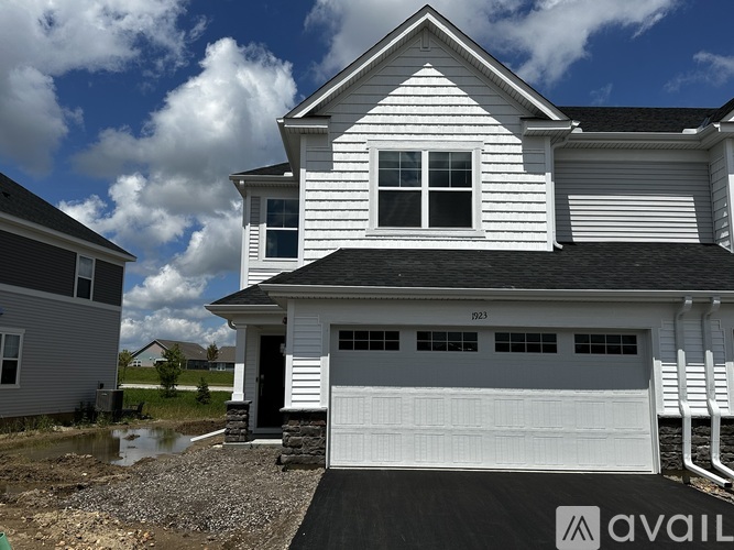 A two-story house with a white garage door is for sale.