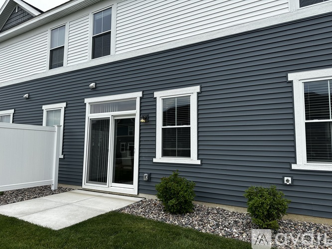 A house with a grey siding and white windows.