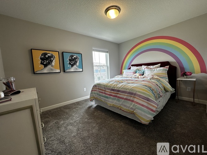 A bedroom with a bed, two pictures on the wall, a nightstand, and a rainbow painted on the wall.