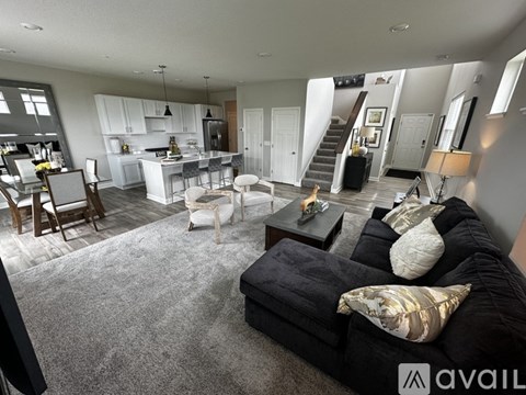 A living room with a black couch and a kitchen in the background.