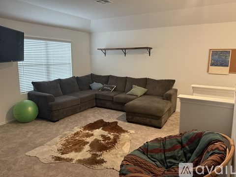 A living room with a grey couch and a green exercise ball.