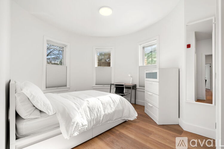 A white bedroom with a bed, desk, and chair.