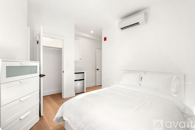 A white bedroom with a large bed and a white dresser.