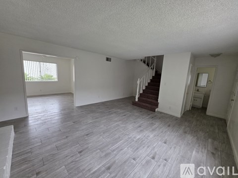 A spacious room with wooden flooring and a staircase leading to another level.