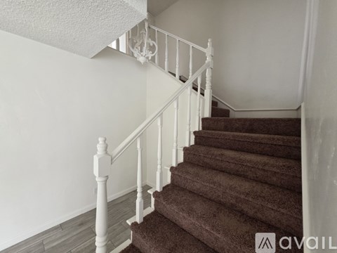 A staircase with a white railing and brown carpeted steps.