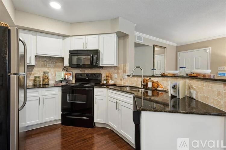 A kitchen with black appliances and white cabinets.