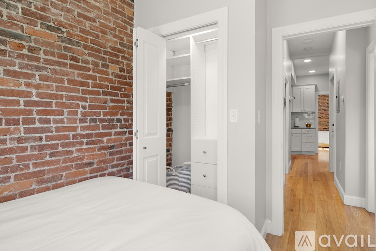 A bedroom with a brick wall and a white bed.