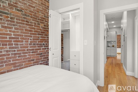 A bedroom with a brick wall and a white bed.