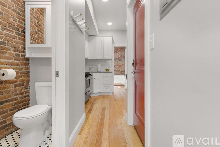 A white toilet is in a bathroom with a brick wall.