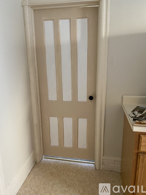 A white door with a black handle is in a room with a carpeted floor.