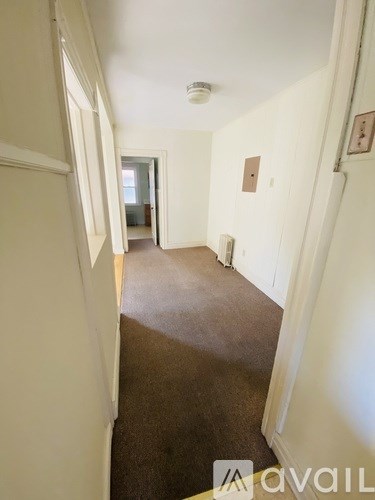 A long hallway with a carpeted floor and white walls.
