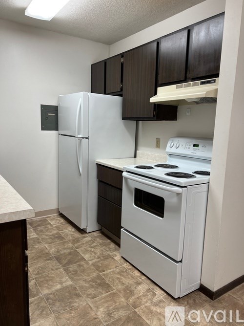 A kitchen with a white fridge, white stove, and brown cabinets.