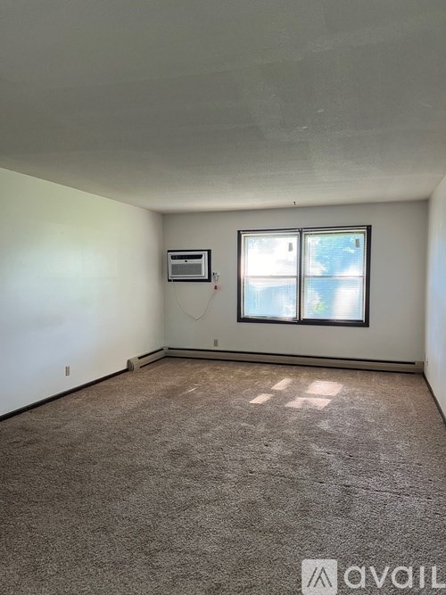 A room with a window and a carpeted floor.