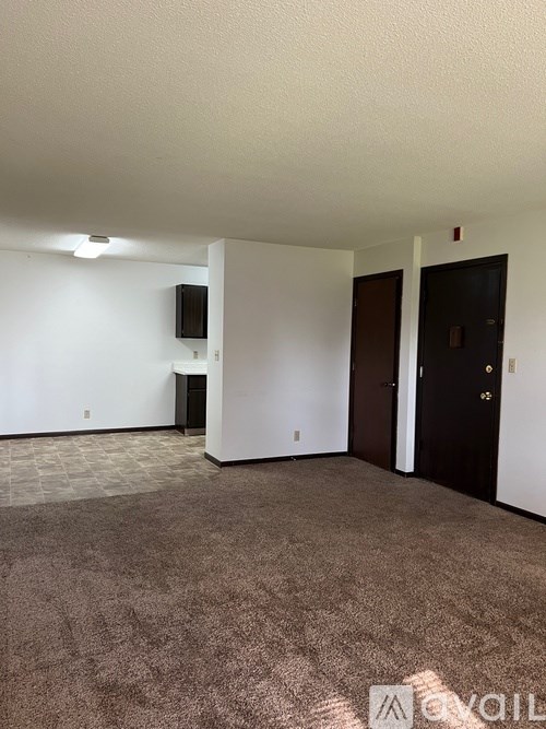 A carpeted room with a door and a wall-mounted speaker.