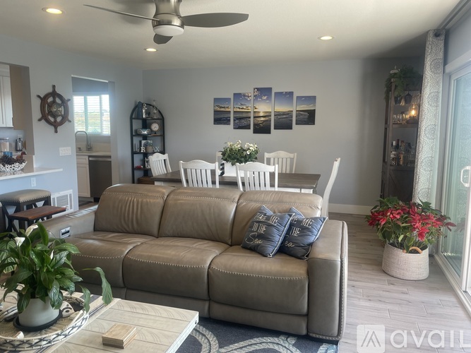 A living room with a grey couch and a ceiling fan.