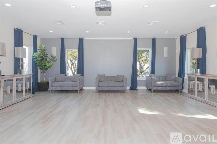 A spacious living room with grey sofas and a wooden floor.