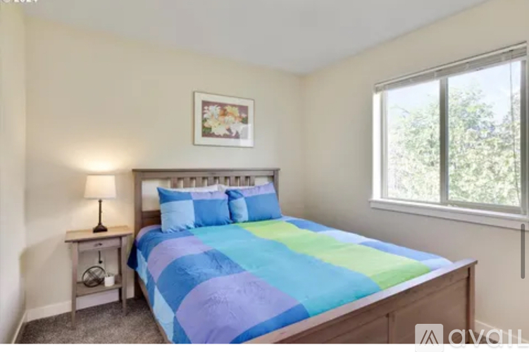 A bedroom with a bed, nightstand, and window.