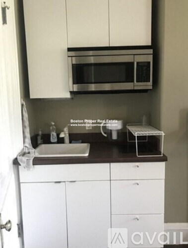 A kitchen with white cabinets and a stainless steel microwave above the sink.