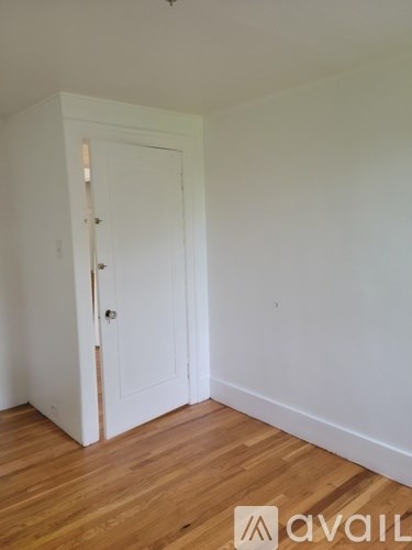 A room with a white door and wooden floor.
