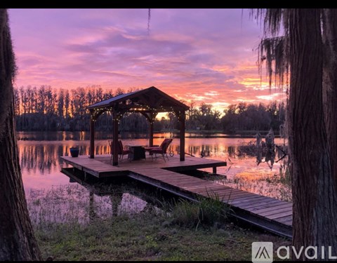 A gazebo is situated on a wooden platform over a lake.