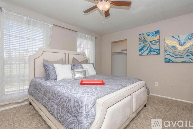 A bedroom with a bed, a ceiling fan, and two paintings on the wall.