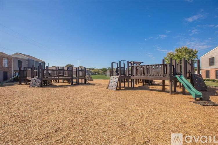 A playground with a green slide and a wooden structure.