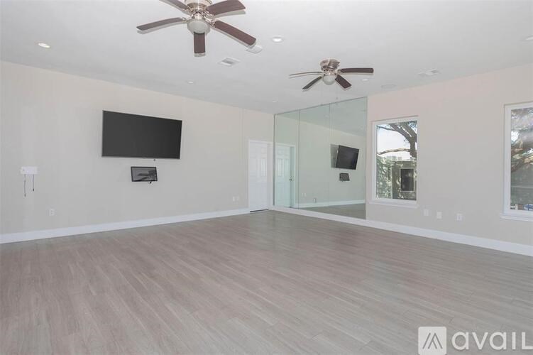 A spacious room with a ceiling fan and a flat screen TV mounted on the wall.