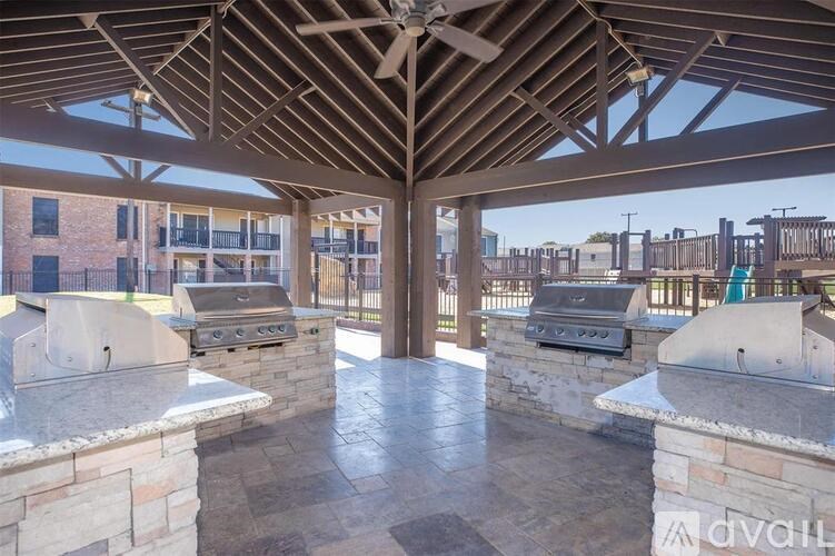 A covered outdoor kitchen area with a grill and a fan.