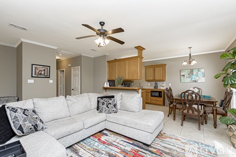 A living room with a grey couch and a ceiling fan.