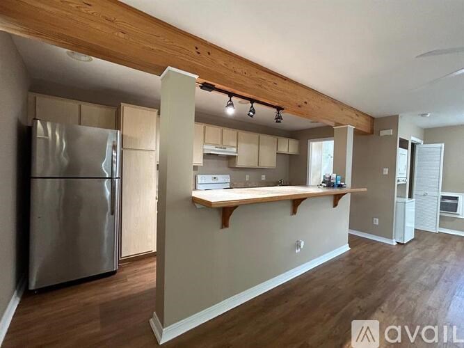 A kitchen with a stainless steel refrigerator and wooden countertops.