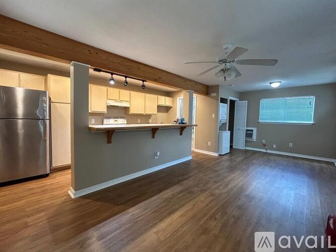 A kitchen with wooden floors and a stainless steel refrigerator.
