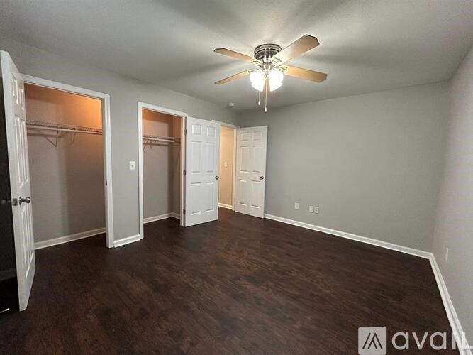 A room with a ceiling fan and wood flooring.