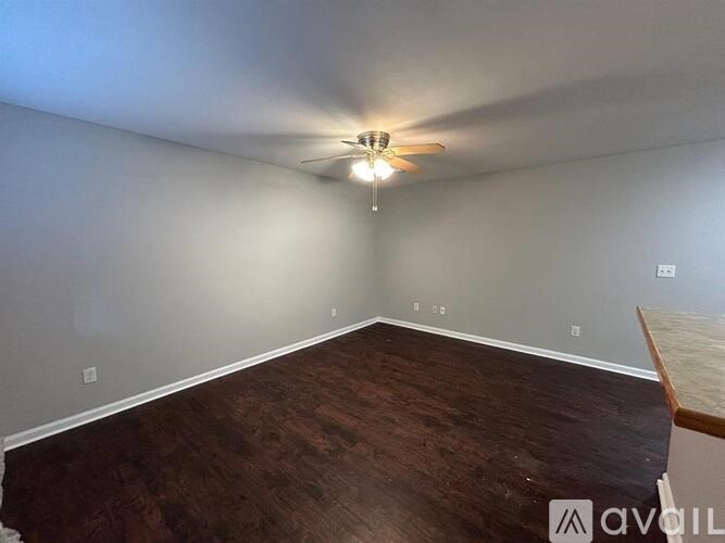 A room with a ceiling fan and wooden flooring.