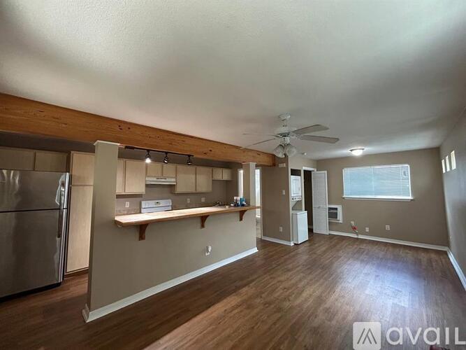 A kitchen with a refrigerator, a counter, and a window.