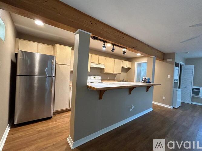 A kitchen with a stainless steel refrigerator and wooden cabinets.