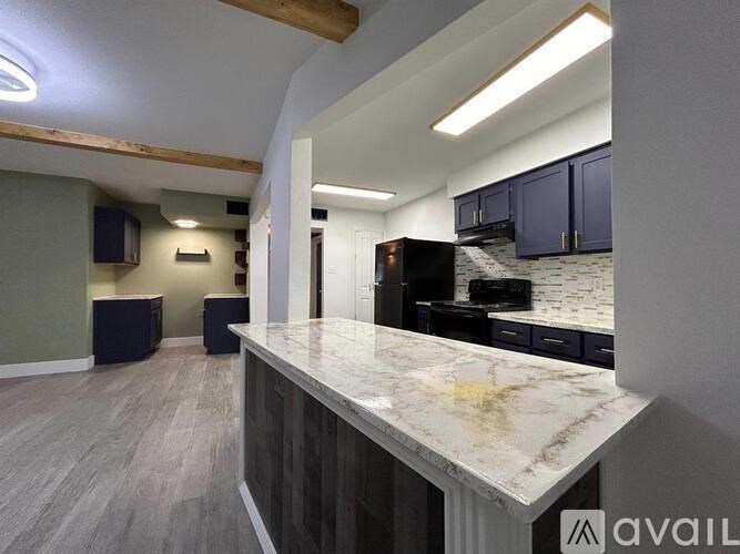 A kitchen area with a marble countertop and a refrigerator.