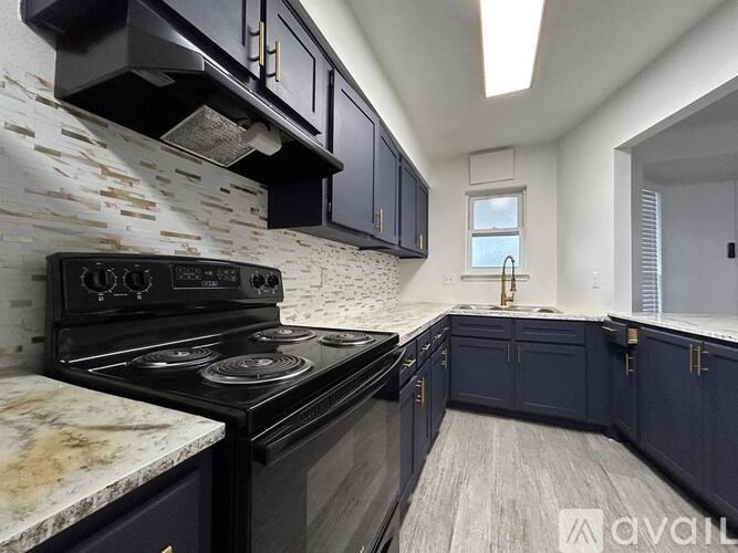 A kitchen with dark blue cabinets and a black stove top oven.